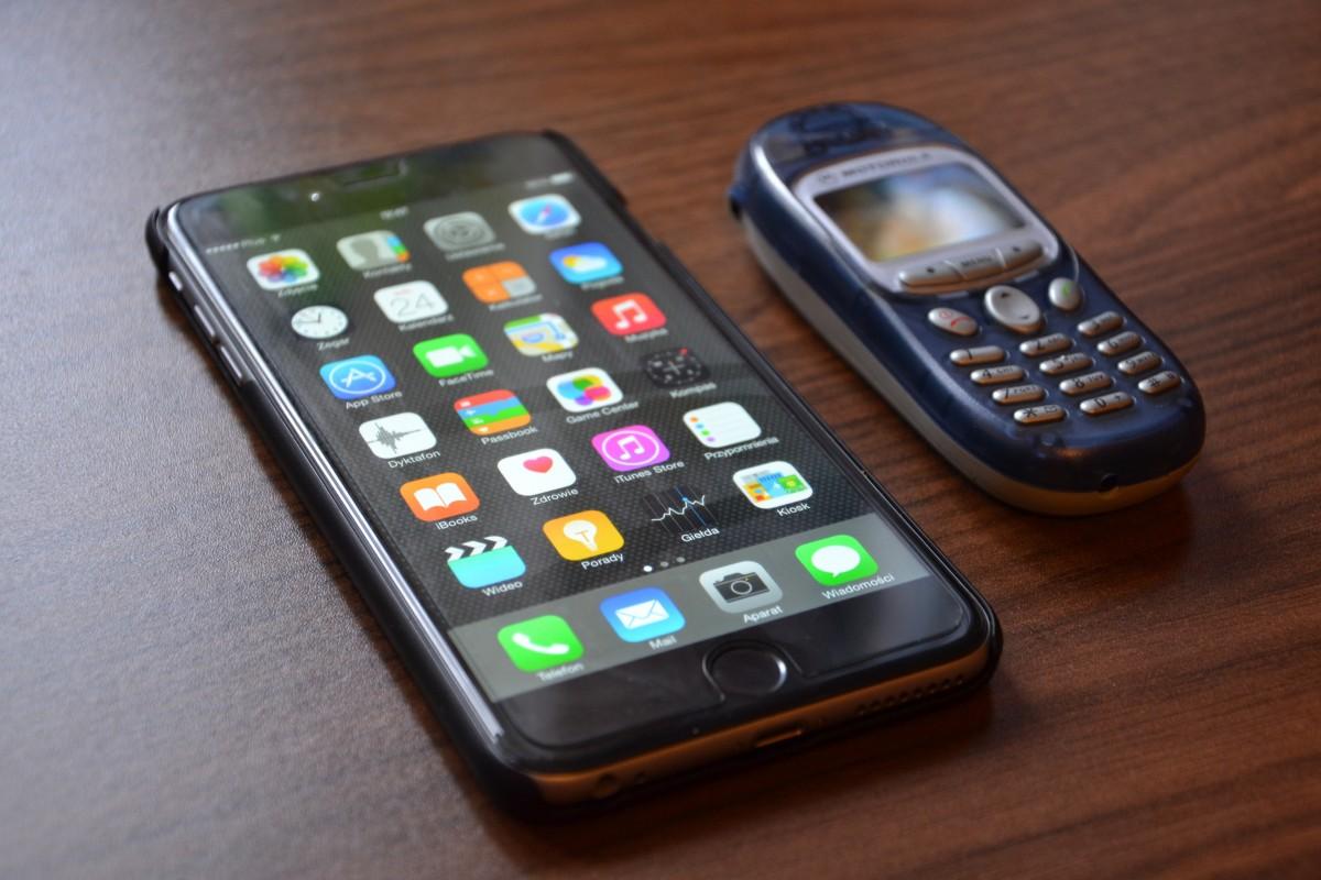 På ett bord ligger en smarttelefon med skärmen full av appar till vänster och bredvid den till höger en 