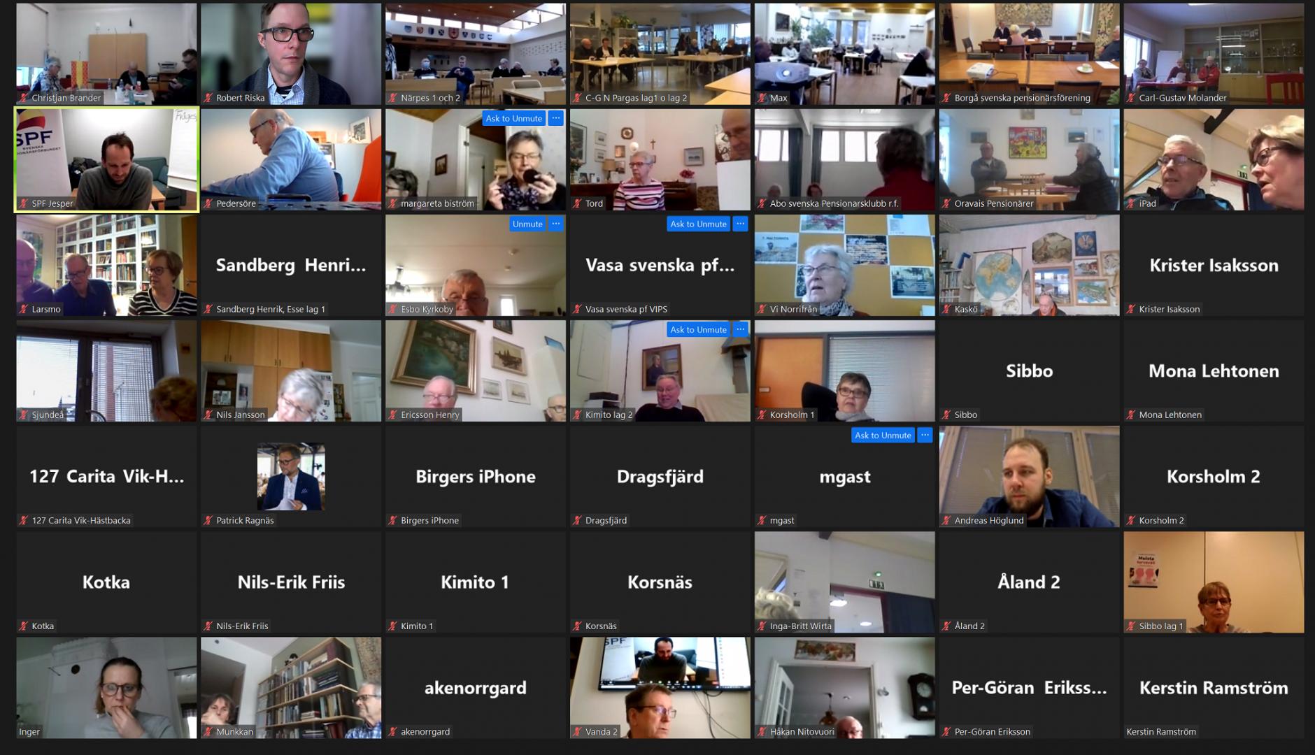 En skärmdump av ett virtuellt möte med flera deltagare, var och en i ett eget videofönster. Vissa fönster visar personer, medan andra visar rum eller är märkta med namn och platser.
