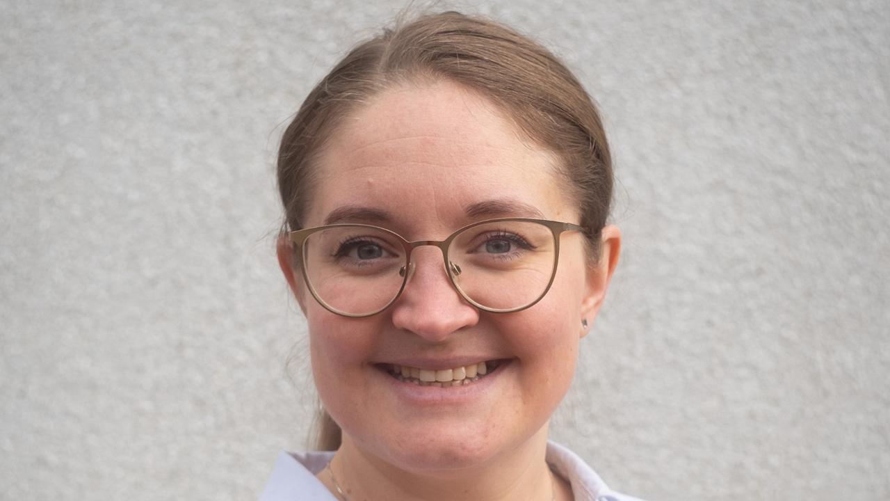 En kvinna med ljusbrunt hår och glasögon ler mot kameran. Hon har på sig en vit skjorta med krage, och bakgrunden är en enkel, ljus vägg.