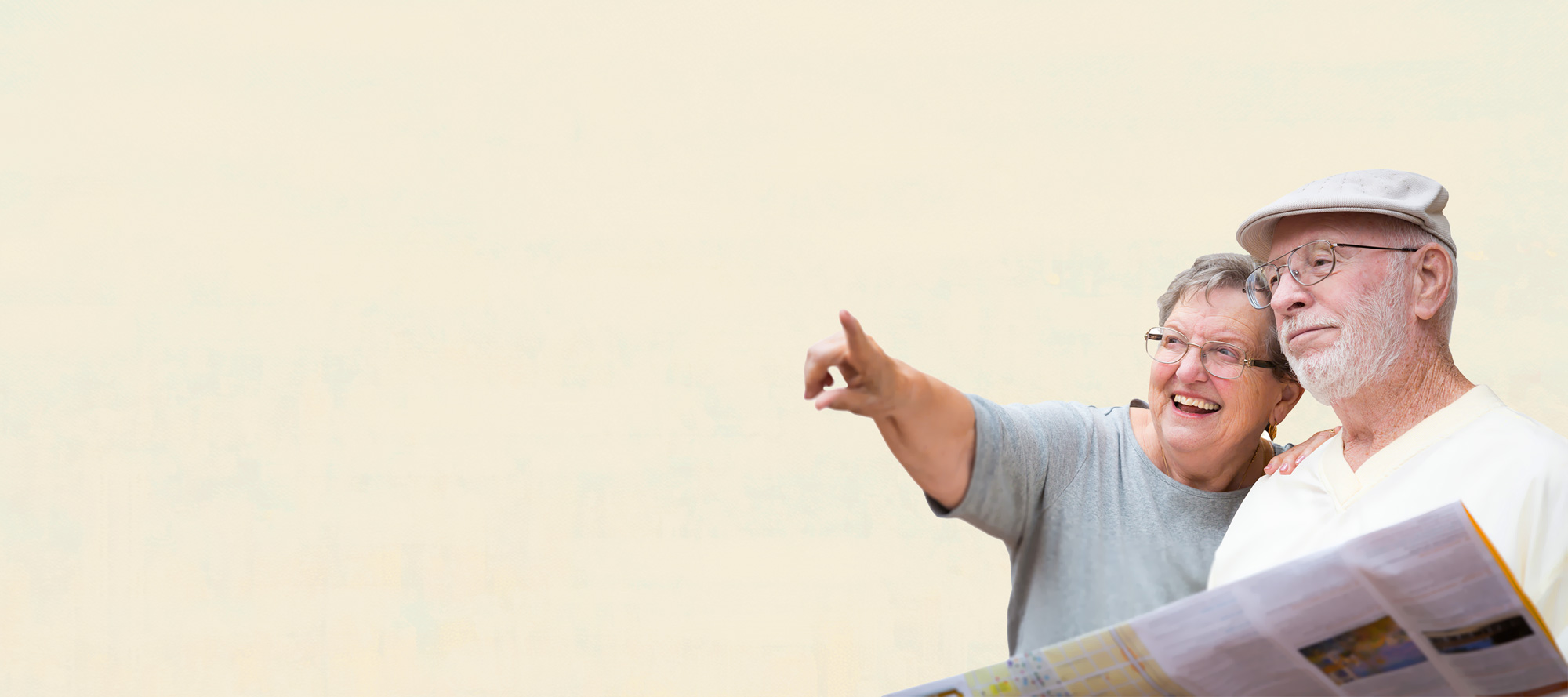 En äldre kvinna ler och pekar ut i fjärran medan hon står bredvid en äldre man som håller i en karta. Båda bär glasögon och är vardagskläder, med en enfärgad ljus bakgrund.