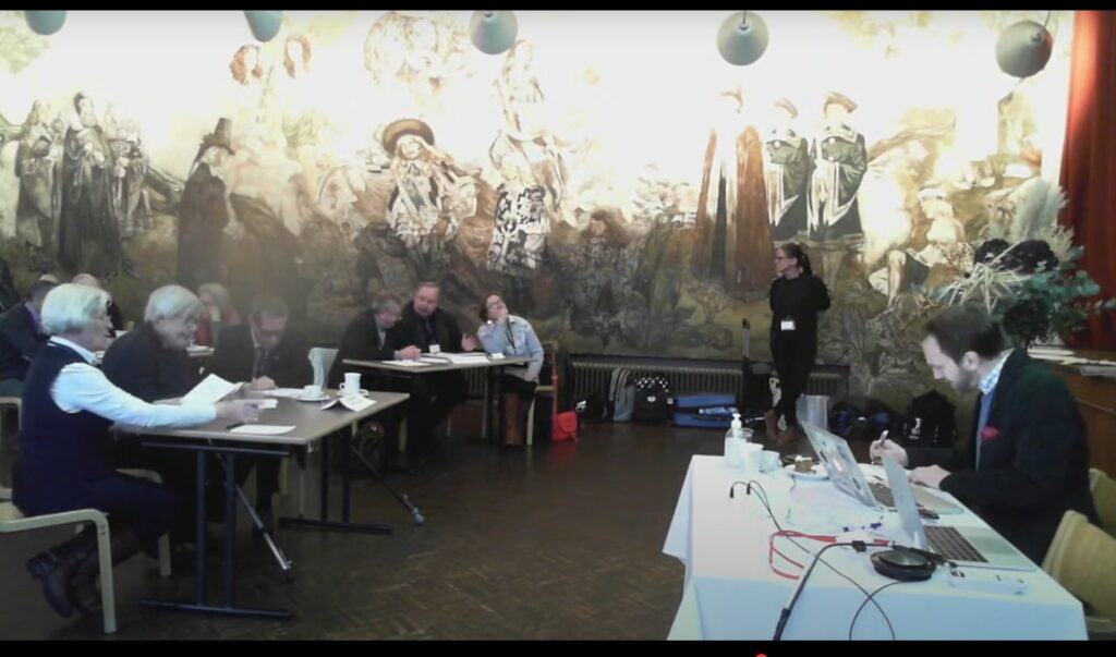 Lagen sitter vid sina bord med papper framför sig.