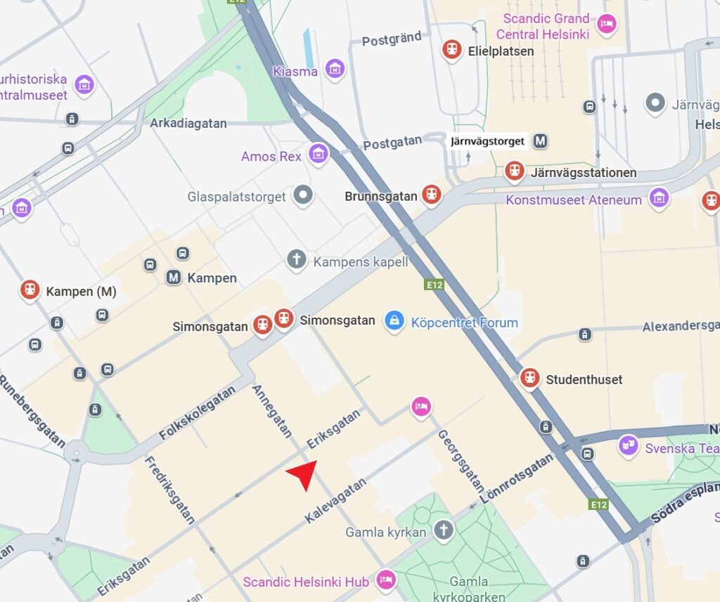 En del av en stadskarta med centrum på Simonsgatan i Helsingfors, Finland, som visar gator, landmärken, tunnelbanestationer och en röd pil som pekar på en plats nära korsningen Eriksgatan och Simonsgatan.